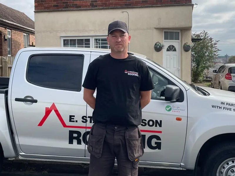 Elias Stanley, owner of E Stanley & Son Roofing, in front of the company van